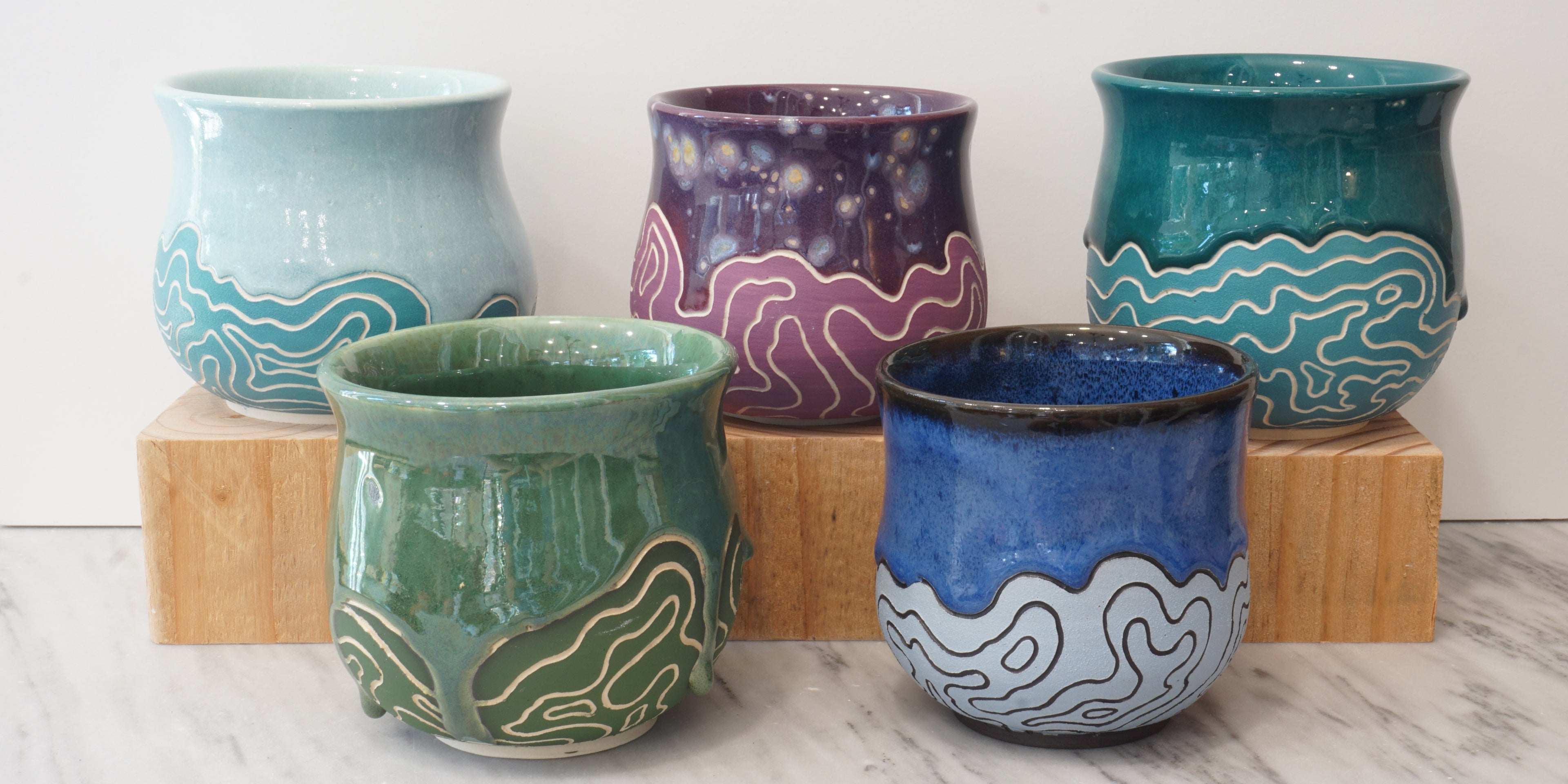 Image showing five brightly colored handmade mugs featuring a topographic map pattern